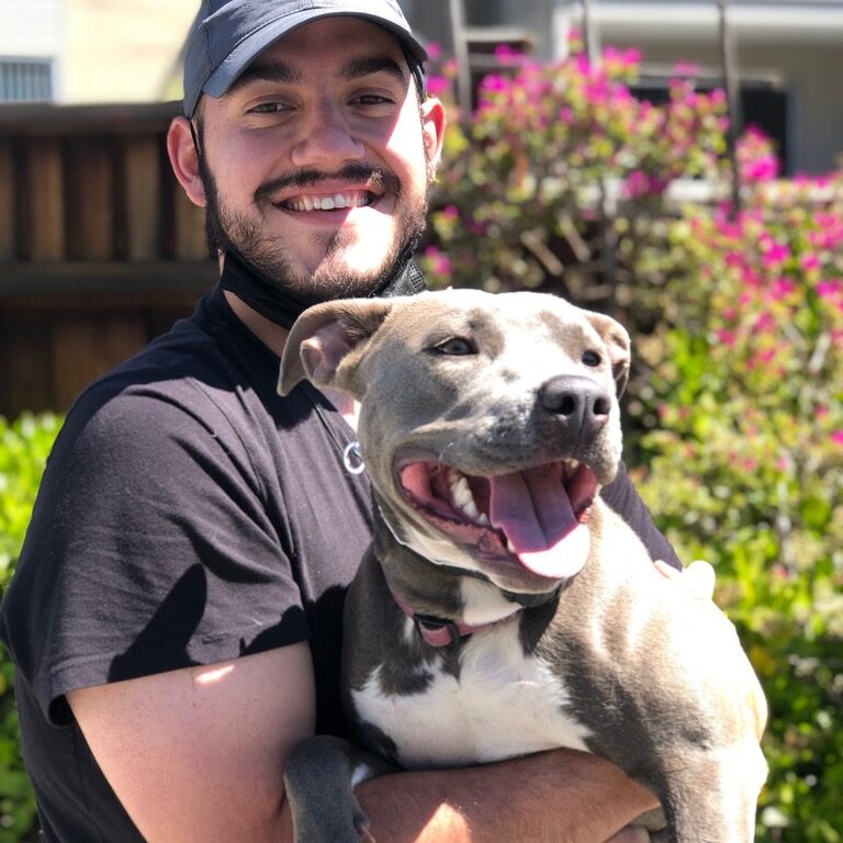 A man holding his dog in the arms of another person.